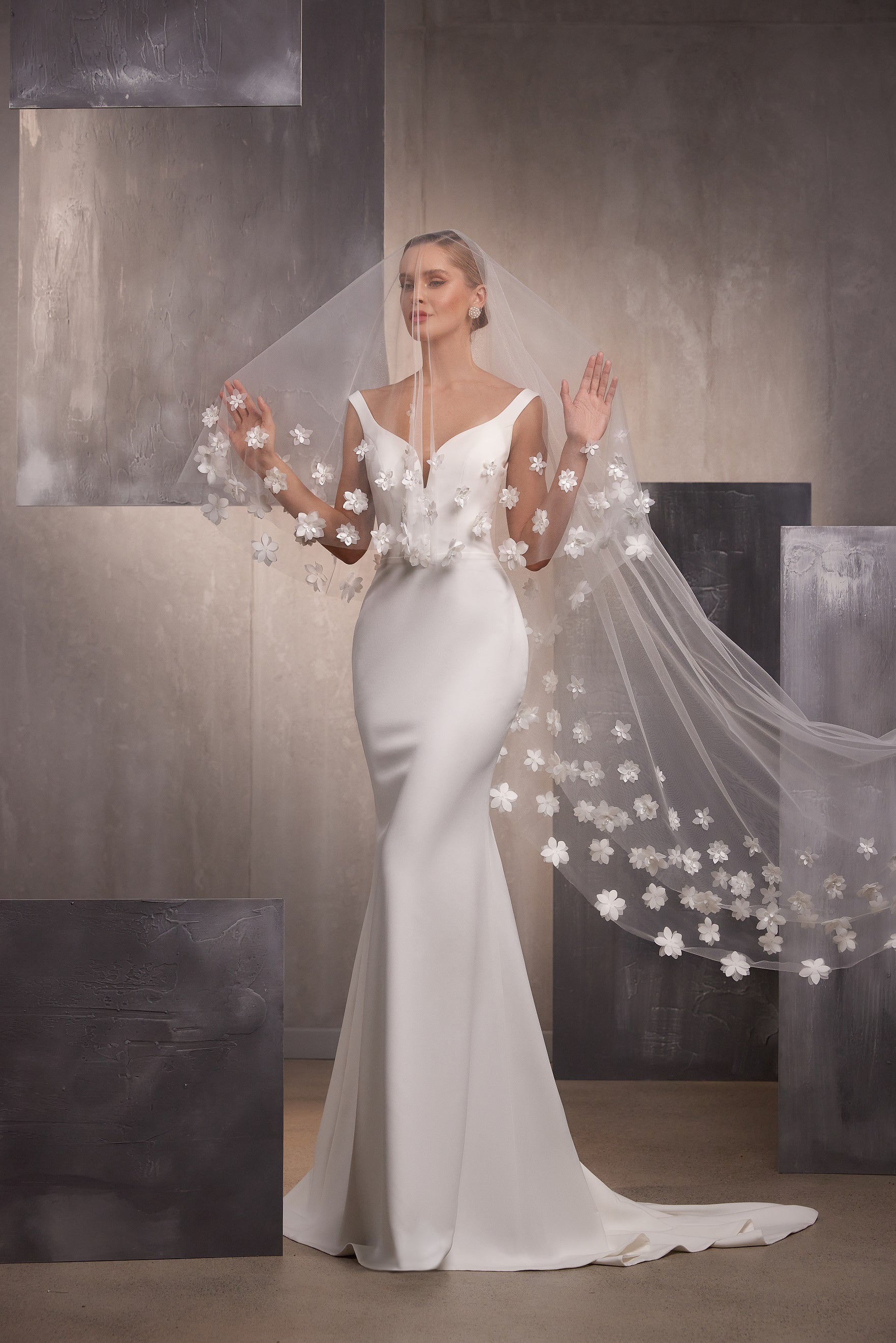 Sheer wedding veil with voluminous white floral embroidery and sparkling accents cascading beside a fitted gown