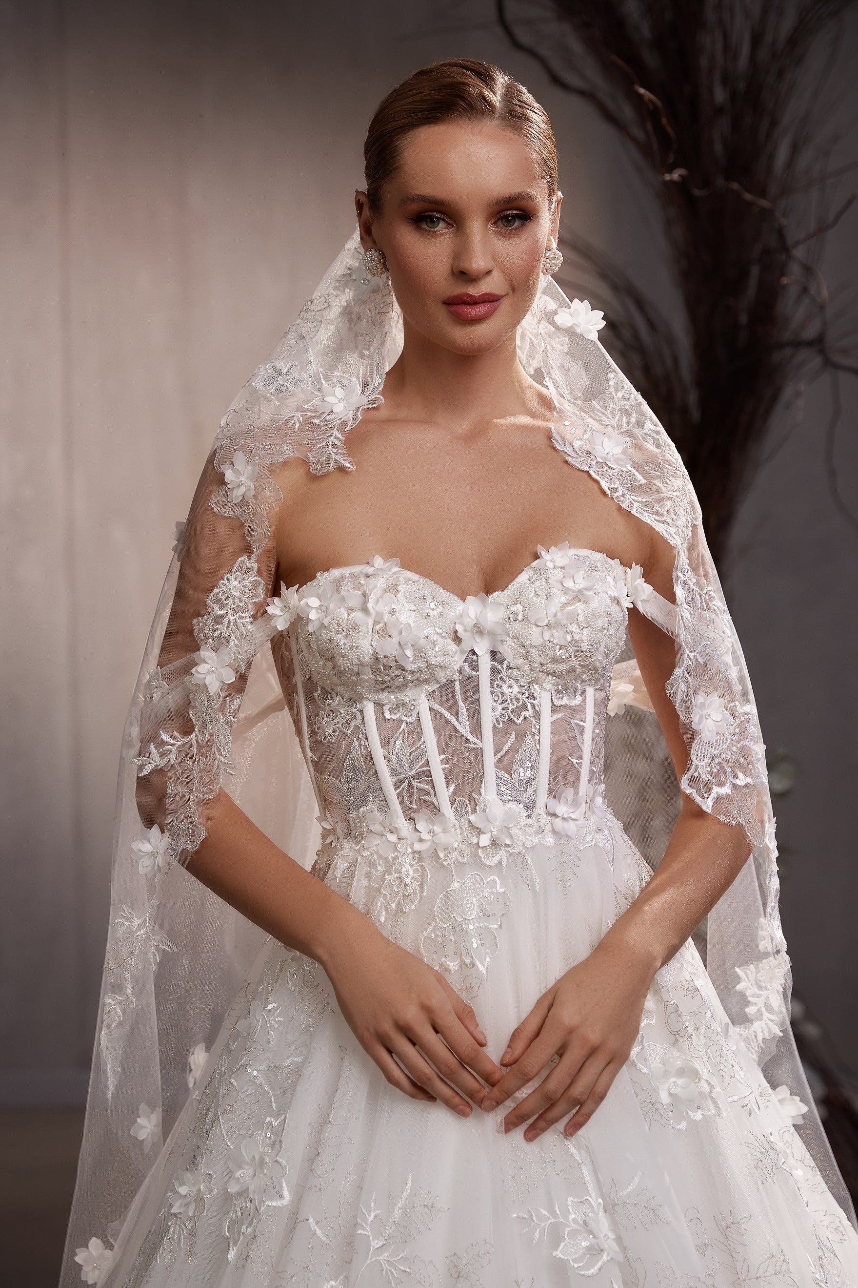 White wedding veil with floral lace appliqués, silver embroidery, and sequins draped over the shoulders