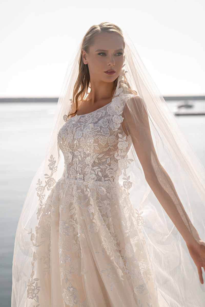 Ivory A-line wedding dress with an asymmetrical one-shoulder lace neckline and floral appliqués