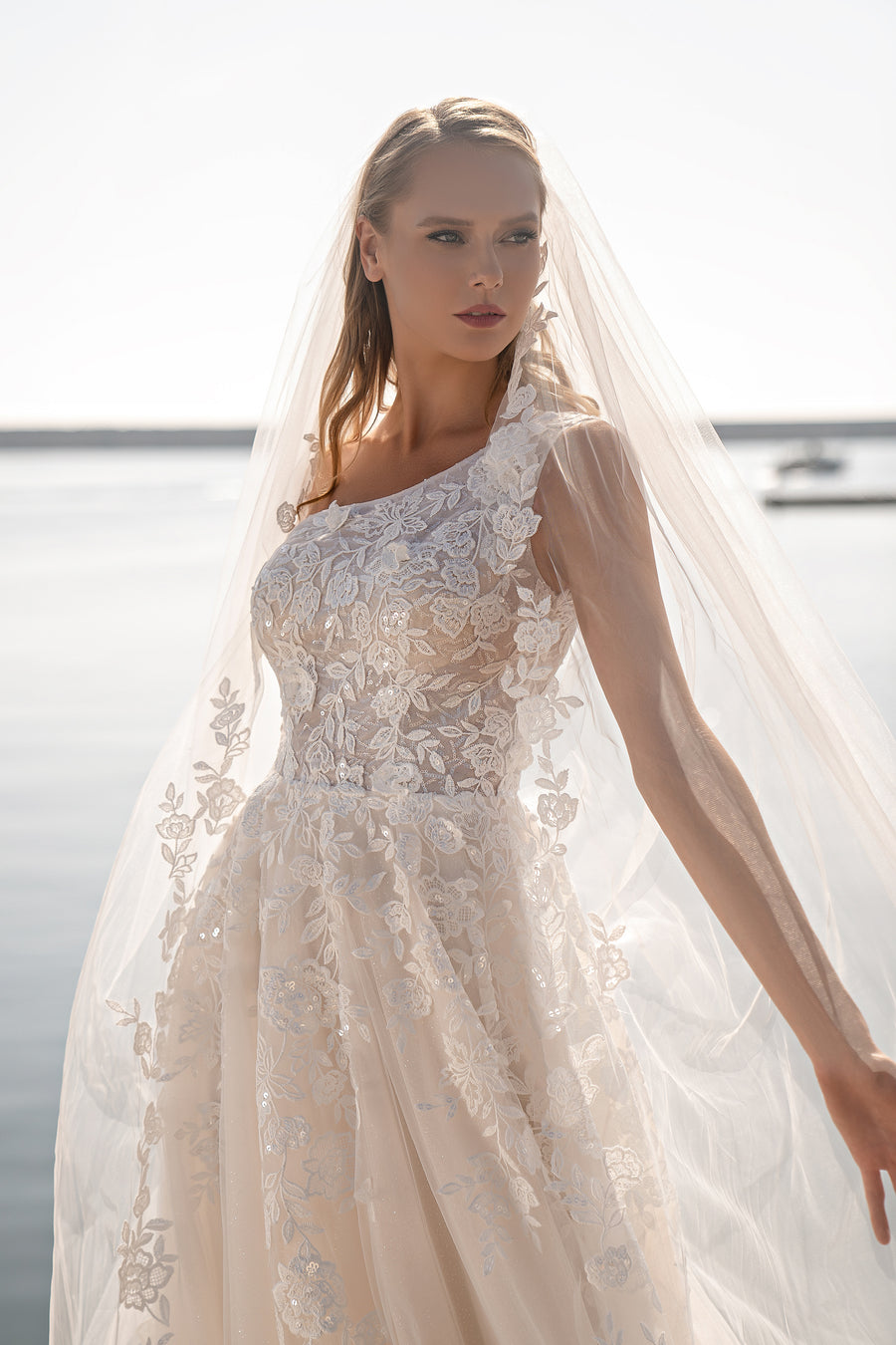 Ivory A-line wedding dress with an asymmetrical one-shoulder lace neckline and floral appliqués