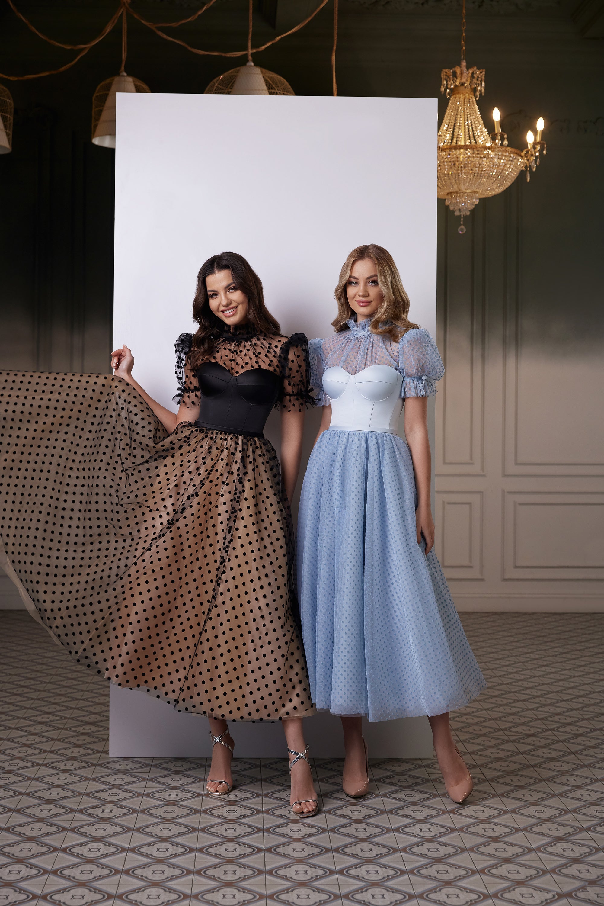 Black polka dot evening dress with a fitted corset bodice, sheer puff sleeves, and a tea-length flared skirt