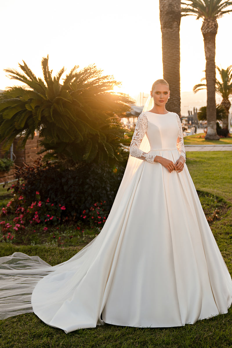 Ivory ball gown wedding dress with a high neckline, embellished sheer sleeves, full skirt, and long train