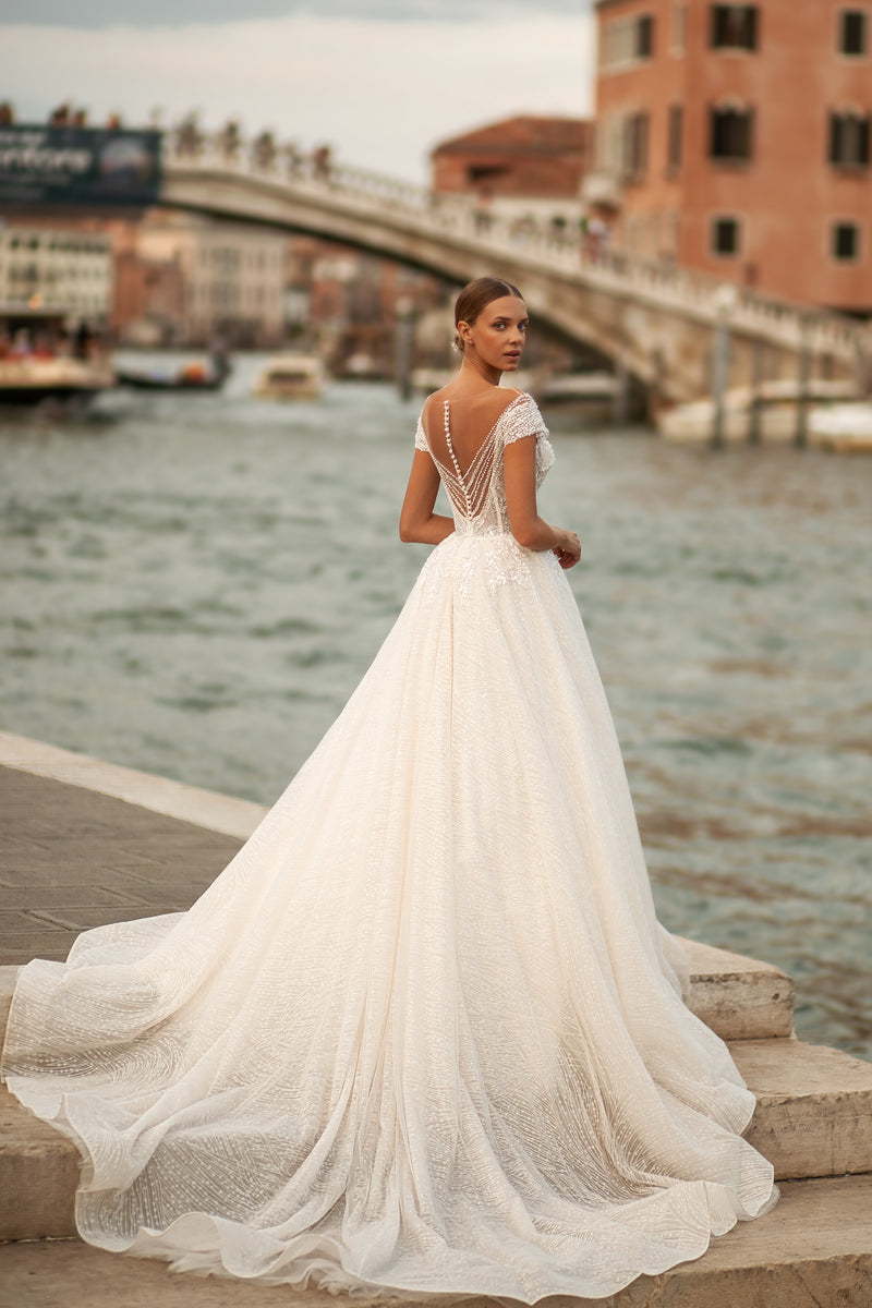 Ivory wedding dress with an open V-back, beaded lace straps, full ball gown skirt, and sweeping train