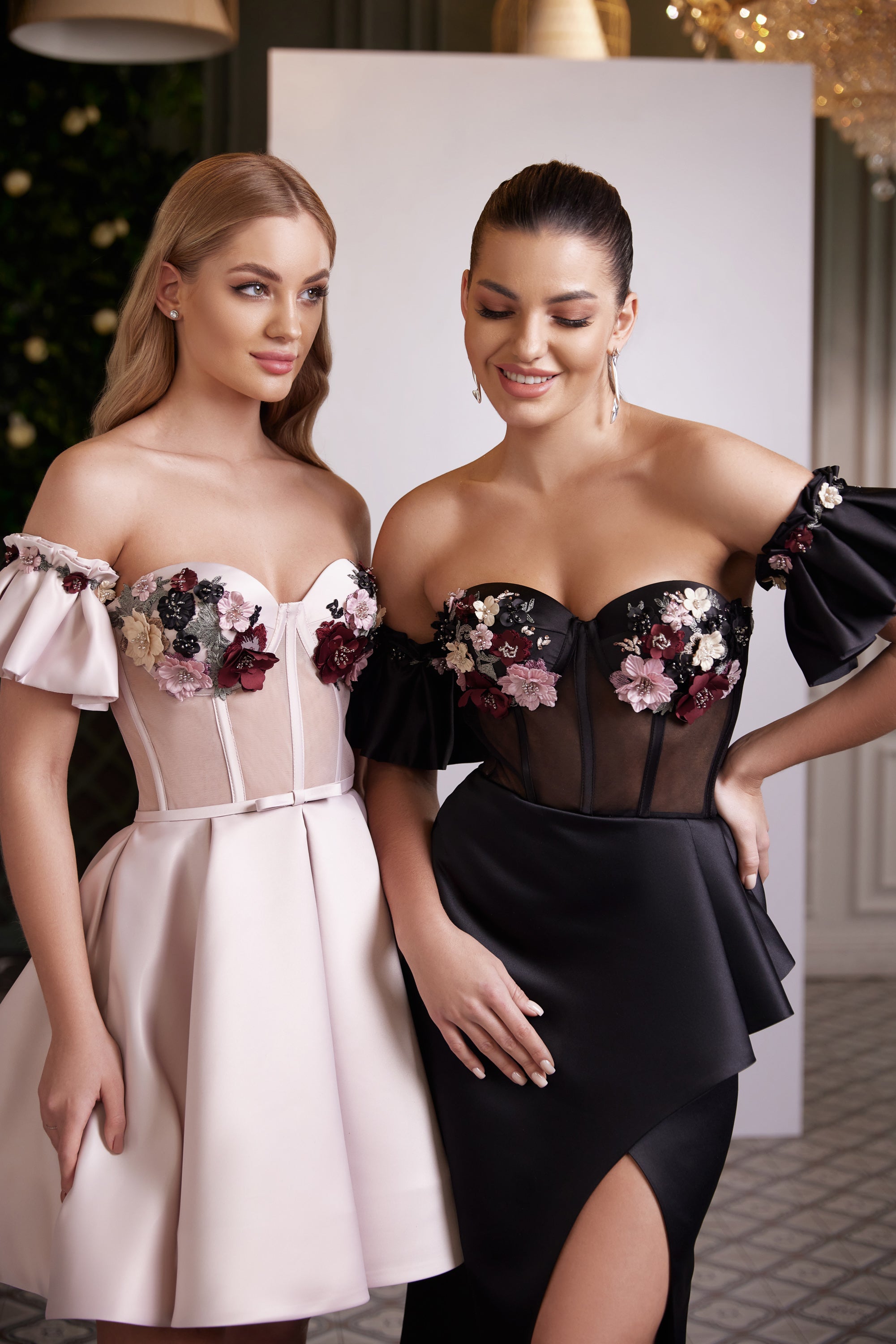 Close-up of floral appliqués on the sheer corset bodices of pink and black off-the-shoulder evening dresses