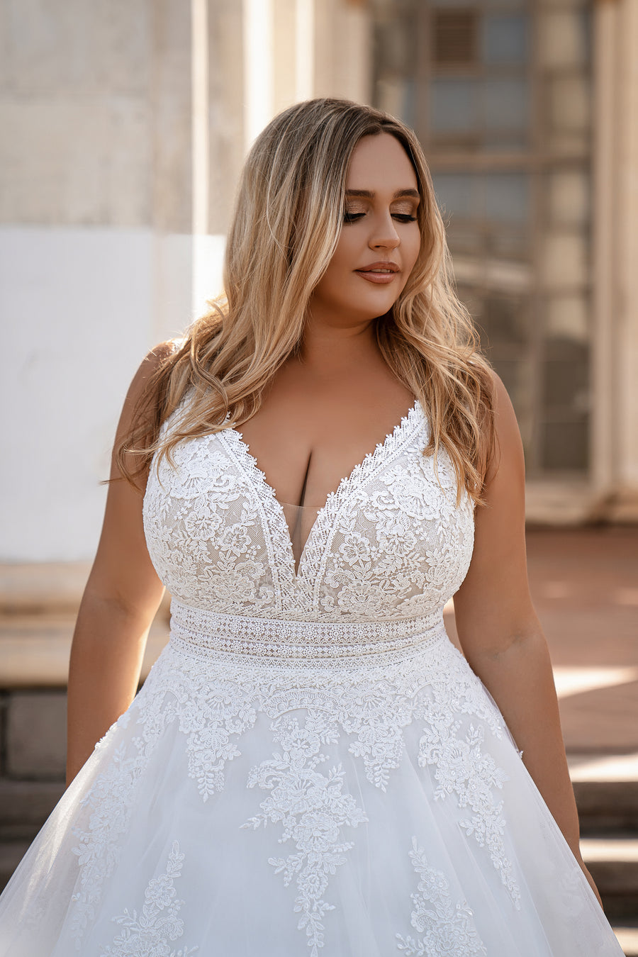 White A-line wedding dress with a plunging V-neckline and floral lace appliqués on the bodice
