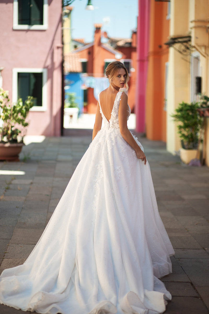Open V-back wedding dress with lace shoulder straps, a full A-line skirt, and a long trailing train