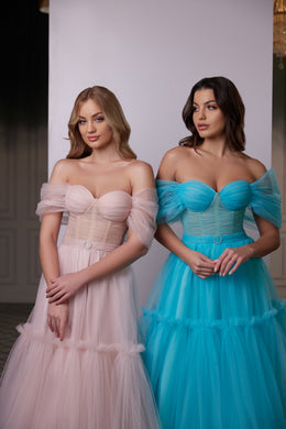 Close-up of a blush pink evening dress with a sweetheart bodice, sheer off-shoulder sleeves, and ruched waist