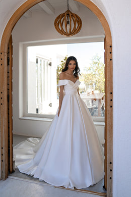 White off-the-shoulder wedding dress with a fitted bodice, full ball-gown skirt, and long train