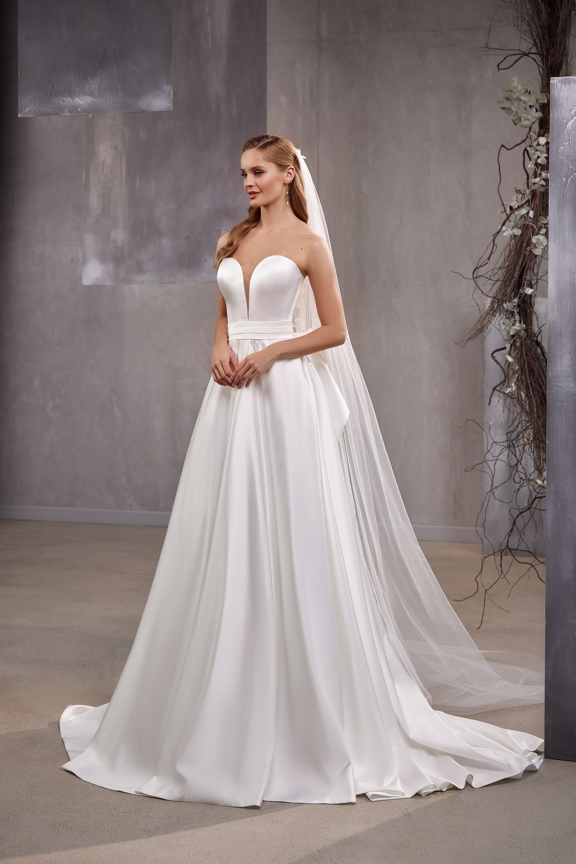 White wedding veil draped over the shoulders, featuring dotted tulle and a long trailing train