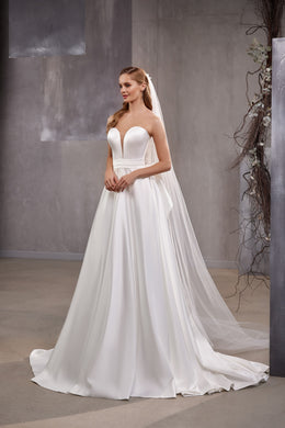 White wedding veil draped over the shoulders, featuring dotted tulle and a long trailing train