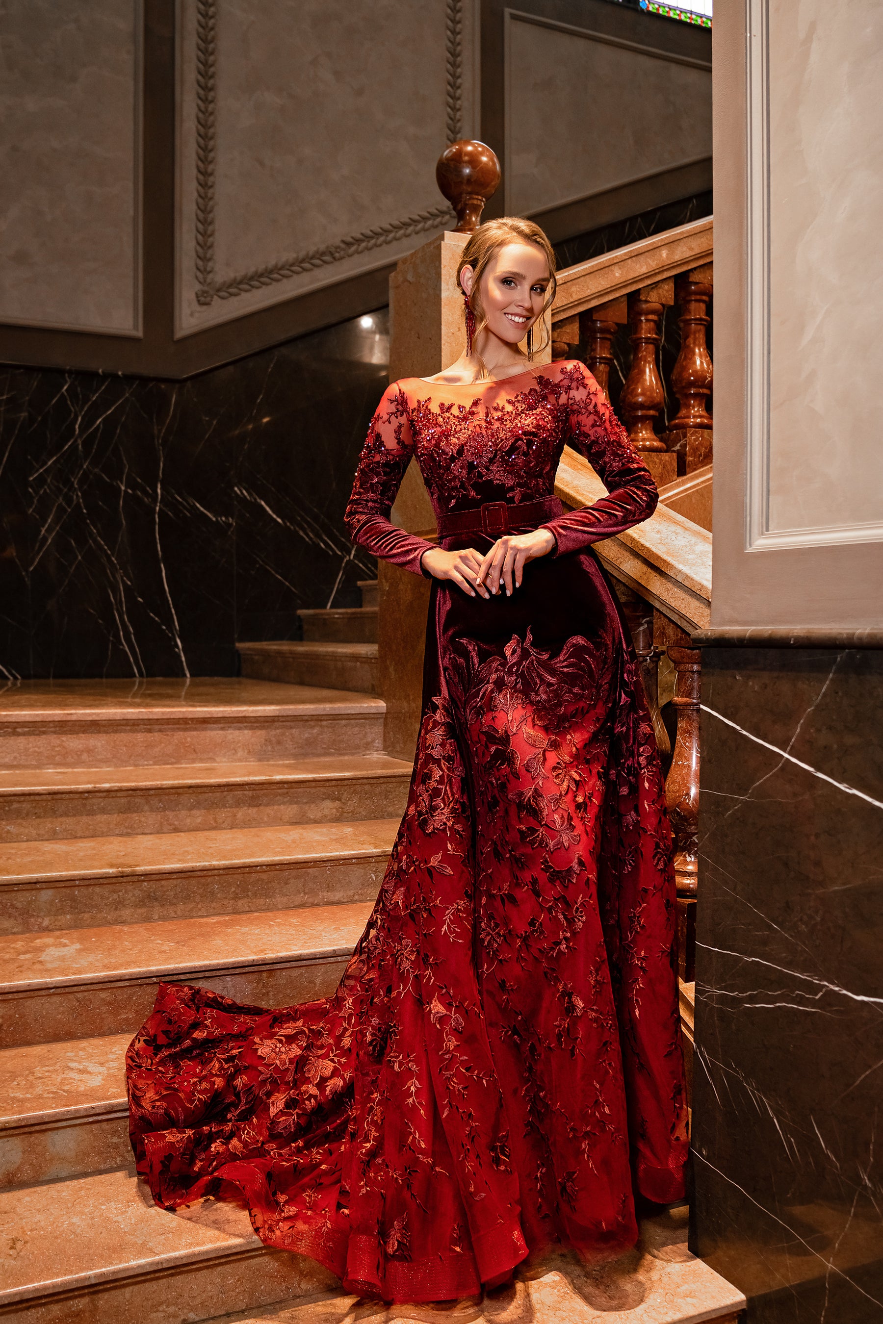 Burgundy velvet evening dress with long sleeves, boat neckline, floral embellishments, and a trailing train