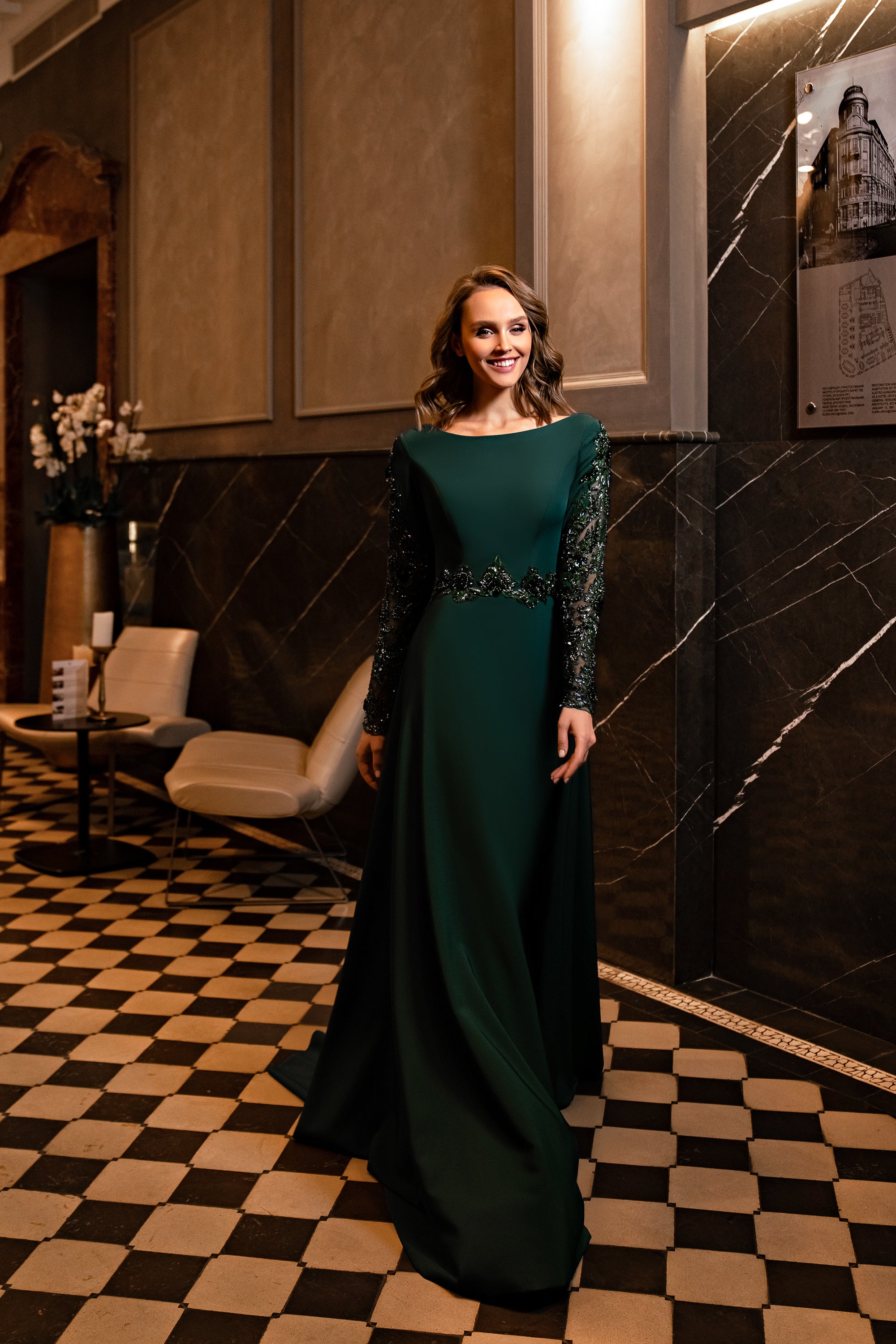 Emerald evening dress with a bateau neckline, long embellished sleeves, beaded waist, and flowing A-line skirt