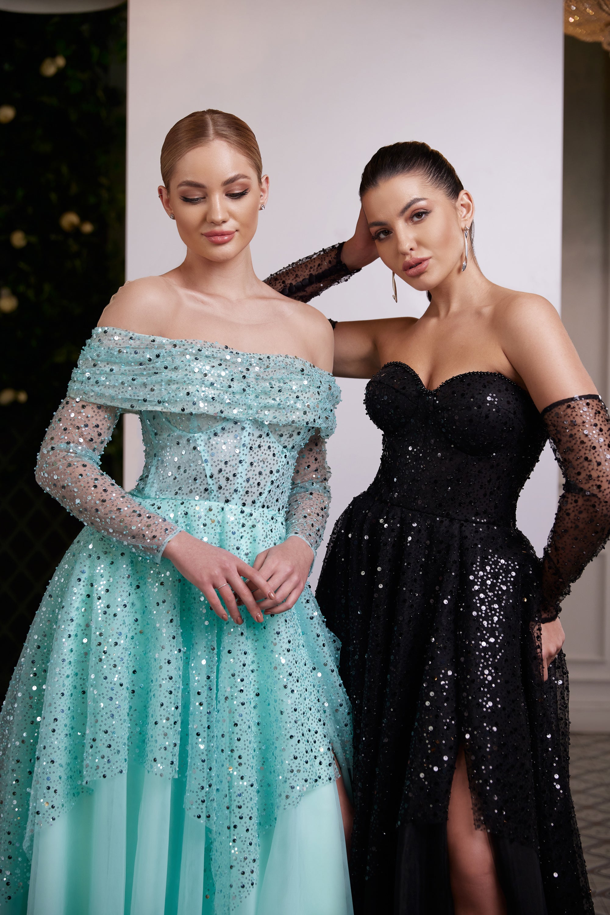 Black sequin evening dress with a sweetheart neckline, sheer sleeves, fitted waist, and high front slit