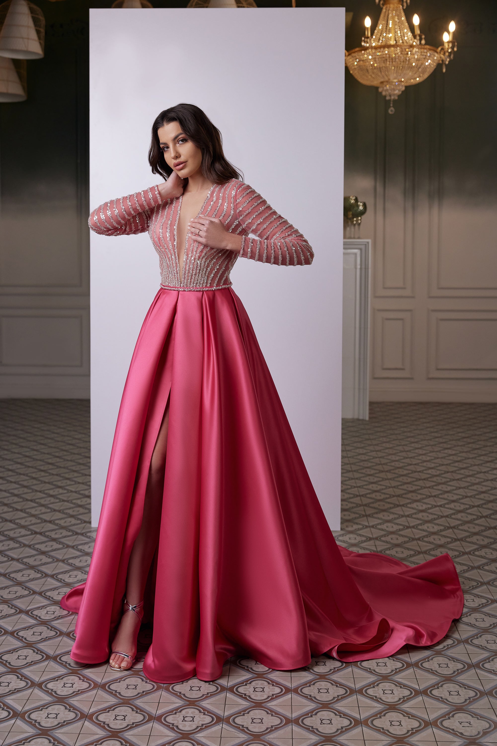 Pink satin evening dress with embellished long sleeves, a fitted bodice, front slit, and flowing train