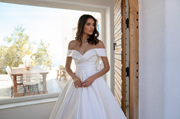 White satin wedding dress with an off-the-shoulder sweetheart neckline and pleated full skirt