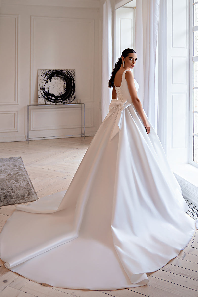 Back of an ivory ball gown wedding dress with an open back, waist bow, and long train
