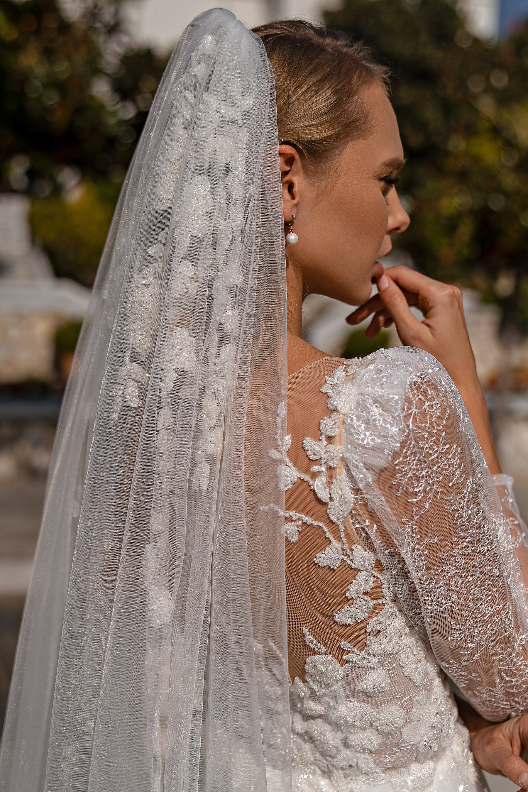 Sheer wedding veil with fine shimmering texture cascading over the back of a lace bridal gown