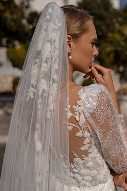 Sheer wedding veil with fine shimmering texture cascading over the back of a lace bridal gown