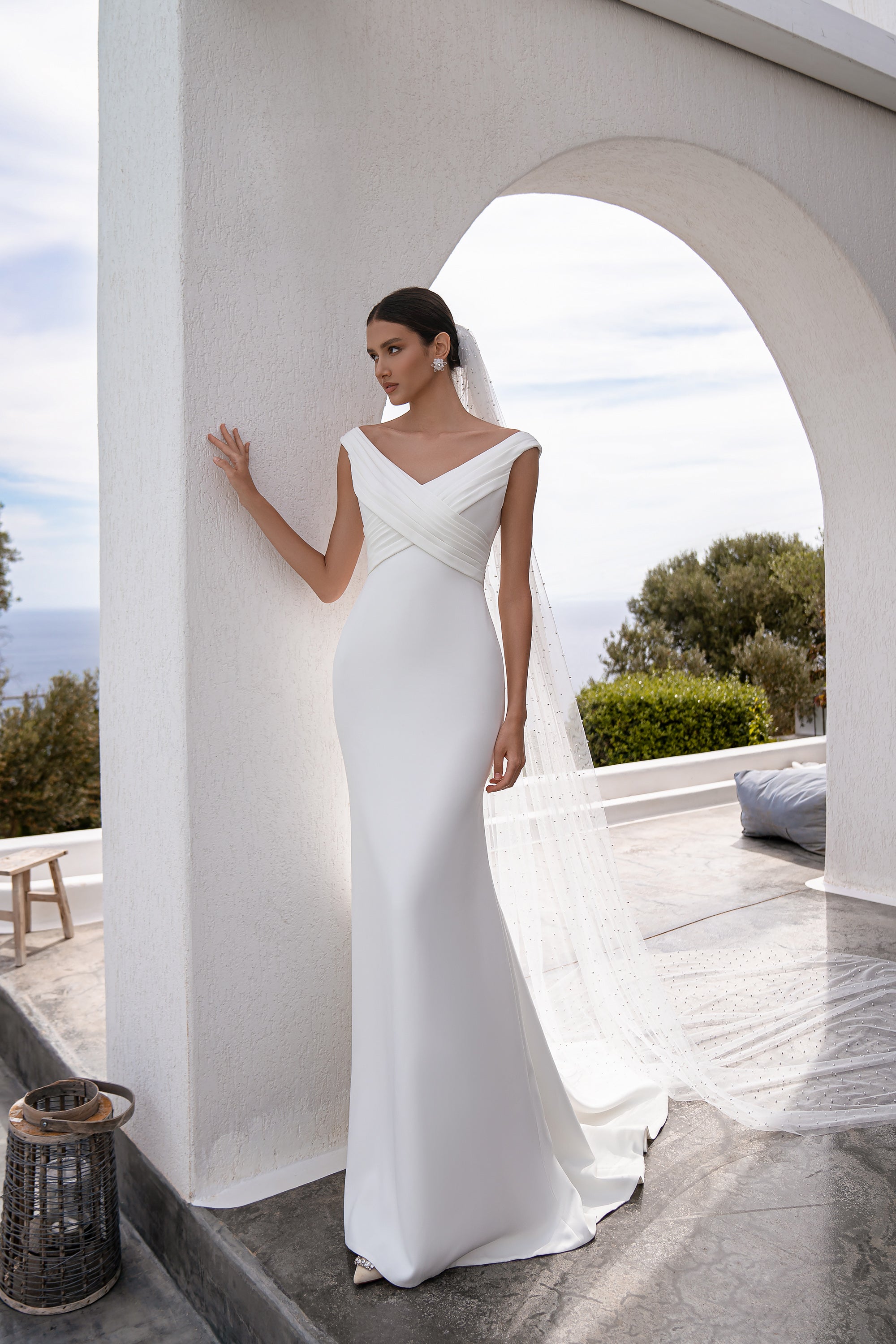 Long white tulle wedding veil with scattered pearl accents, flowing behind the gown