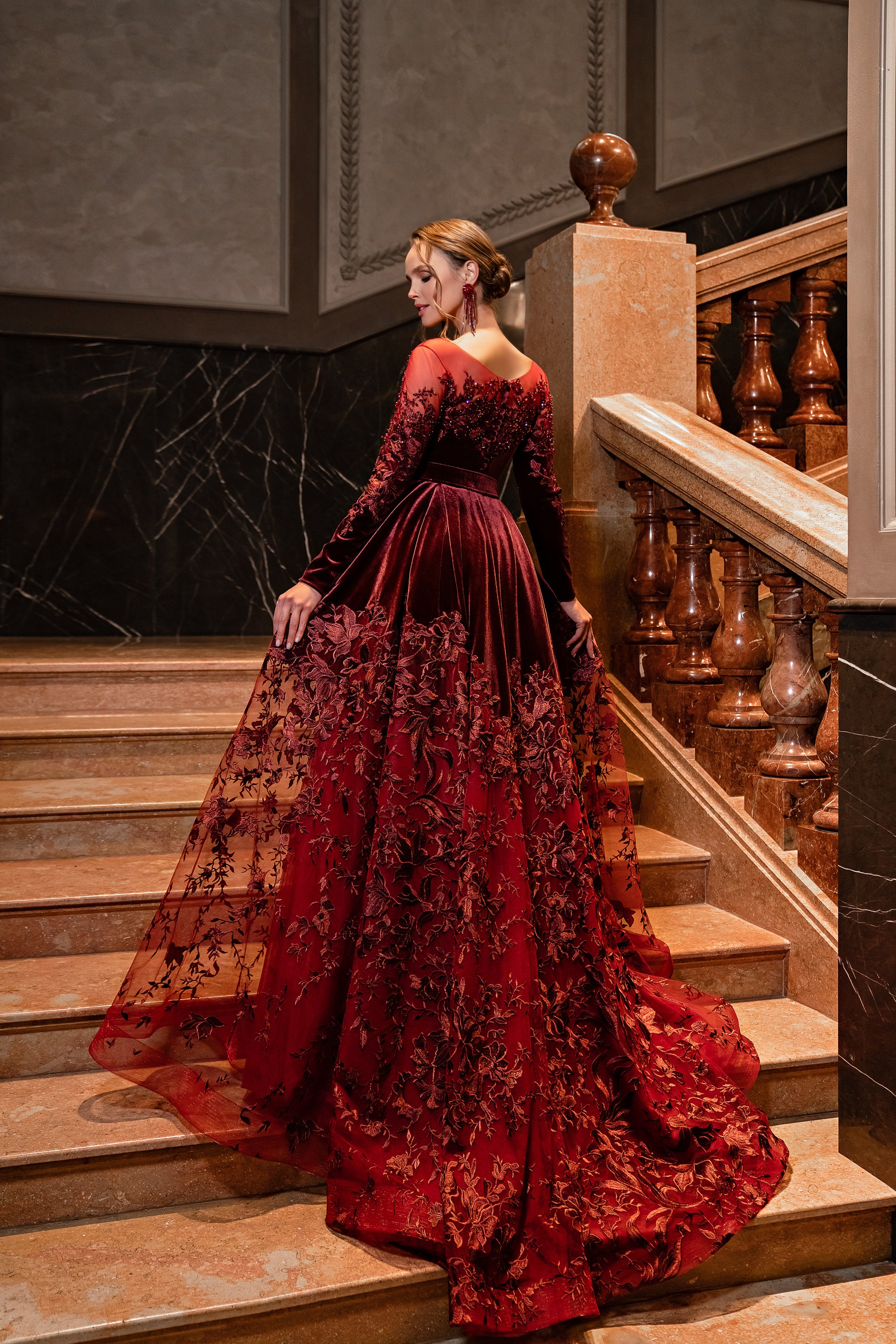 Burgundy evening dress from the back with a low neckline, long sleeves, and a wide embellished train