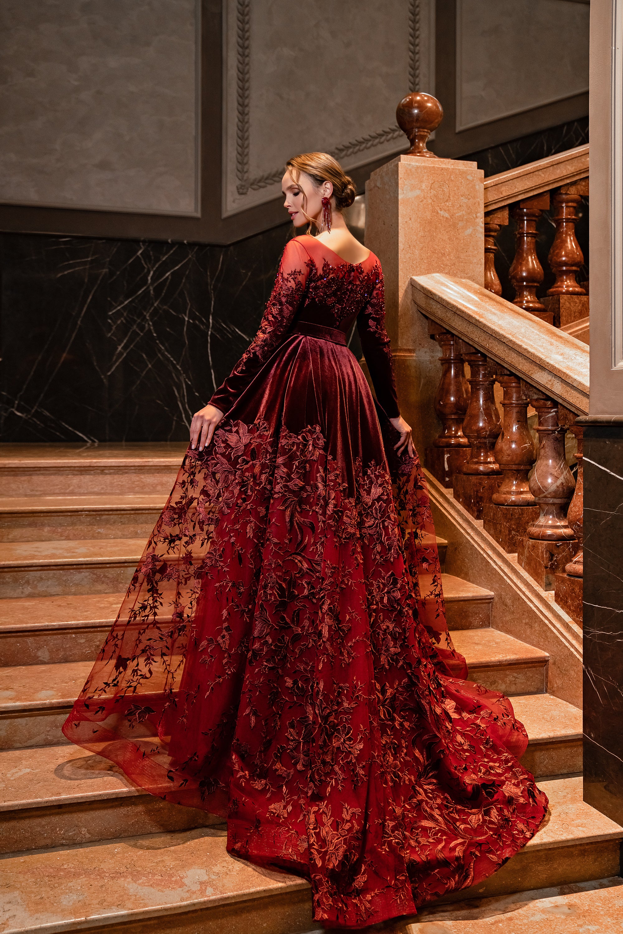 Burgundy evening dress from the back with a low neckline, long sleeves, and a wide embellished train