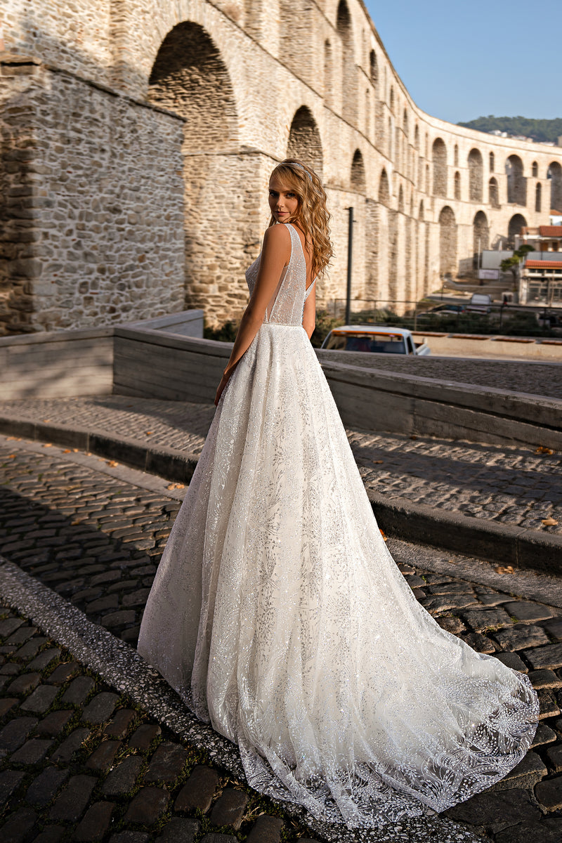 Ivory glitter wedding dress showing an open back, slim straps, full A-line skirt, and sweeping train