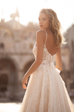 Open low back with floral lace appliqués on an ivory wedding dress with a flowing full skirt