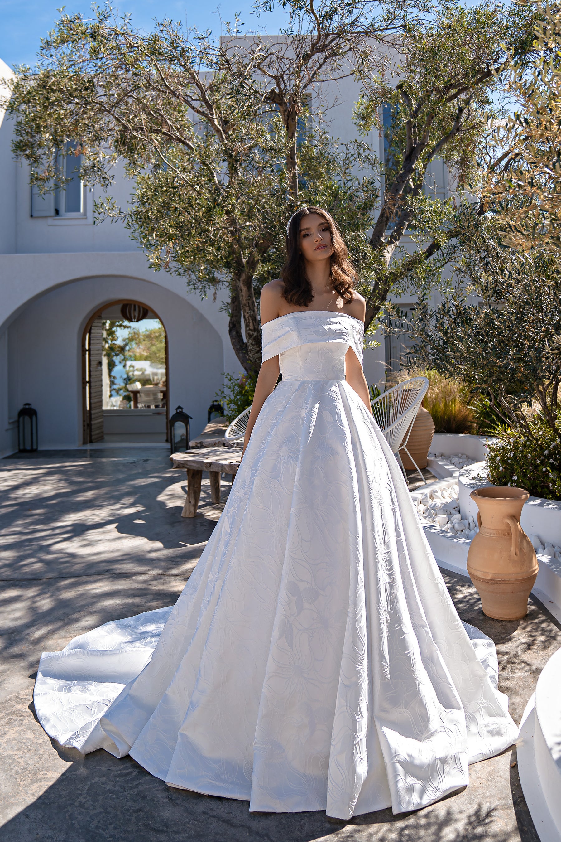 Ivory floral-patterned ball gown wedding dress with an off-the-shoulder neckline and long train