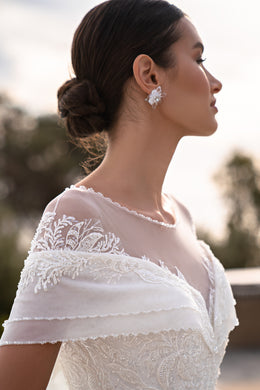 Close-up of the lace shoulder sleeve, sheer illusion neckline, and beaded bodice on a white wedding dress