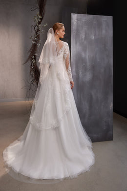 White double-layer wedding veil draped over the back, with floral lace edging and a long flowing spread