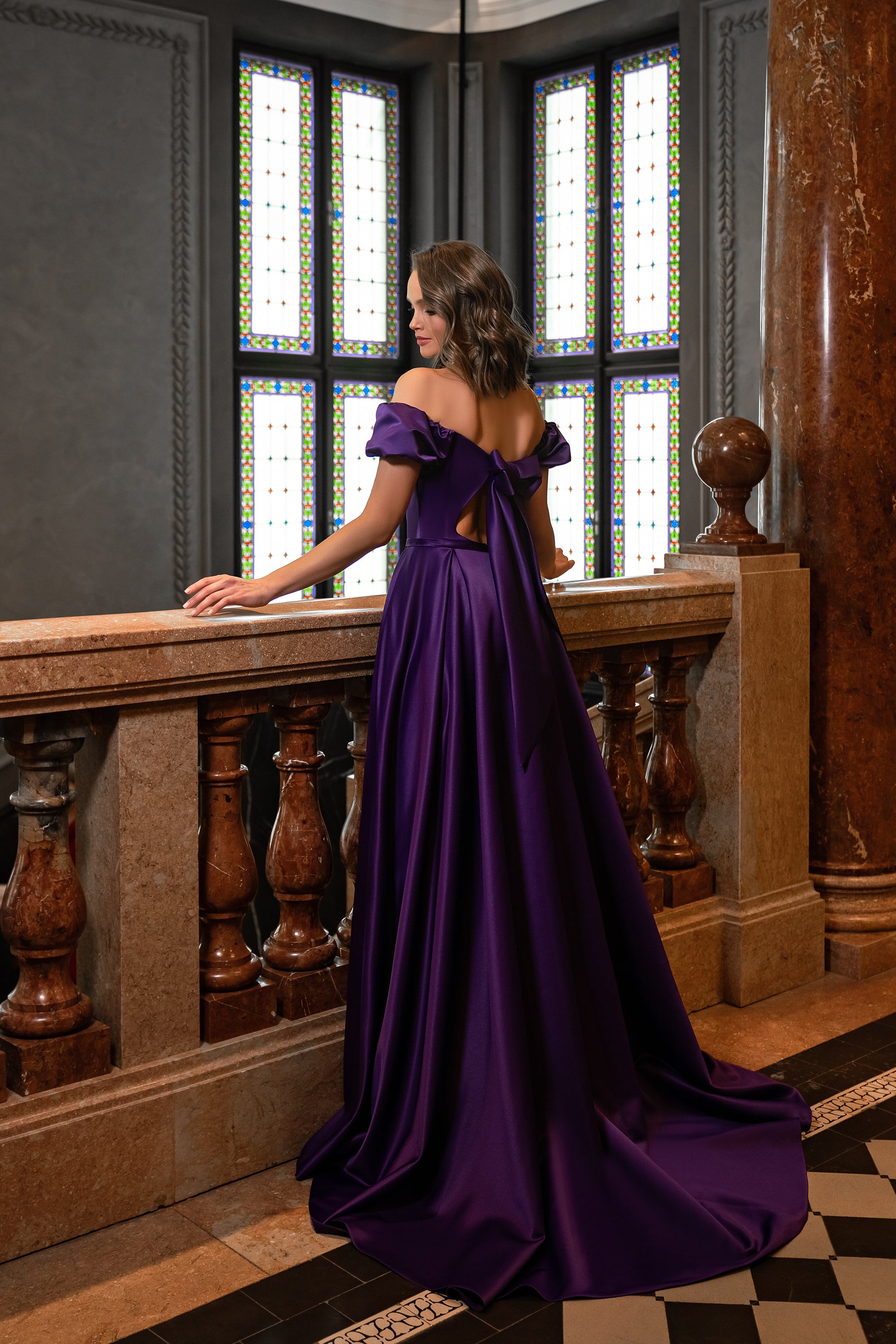 Purple evening dress with an open back, off-shoulder ruffled sleeves, and a sweeping floor-length train