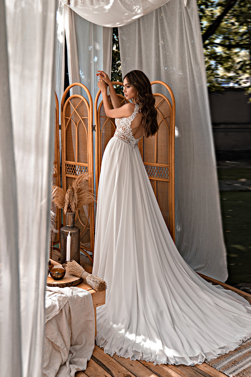 Ivory A-line wedding dress with a flowing pleated skirt, long train, and intricate lace sleeveless bodice