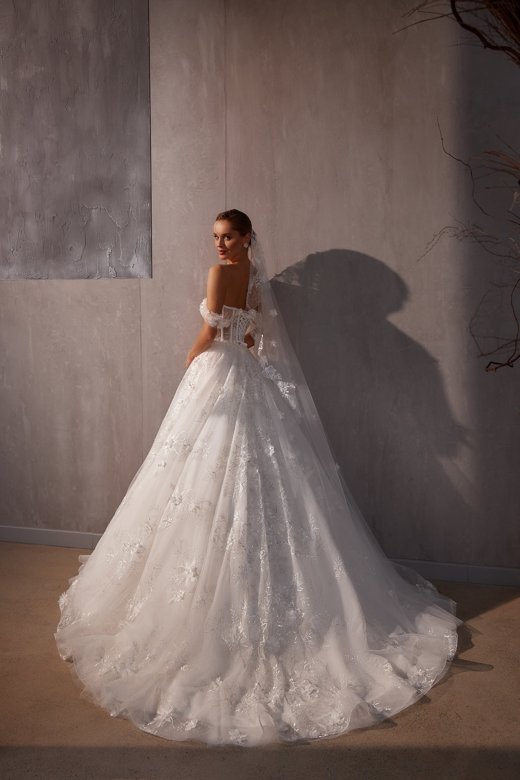 Long white wedding veil flowing into a wide trailing edge with scattered floral appliqués and shimmer