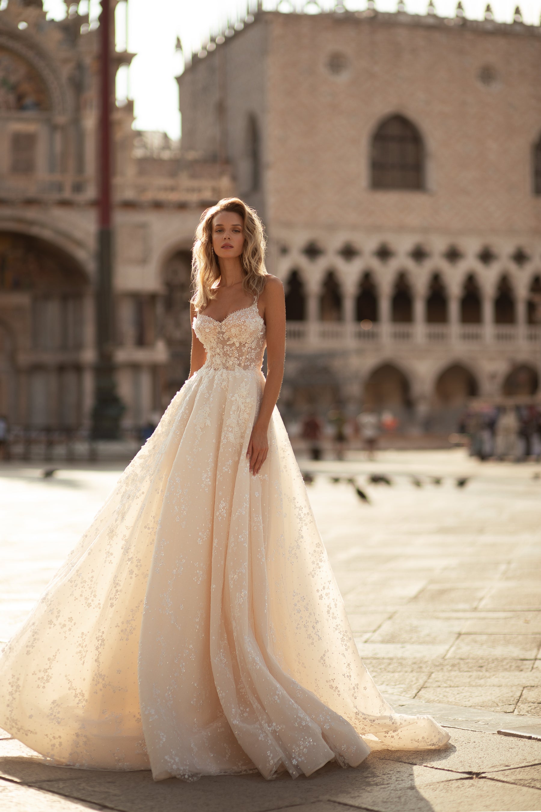 Ivory A-line wedding dress with thin straps, floral lace bodice, and a full sparkling tulle train