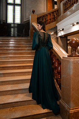 Deep teal evening dress with a sheer lace back, voluminous sleeves, gathered waist, and sweeping train