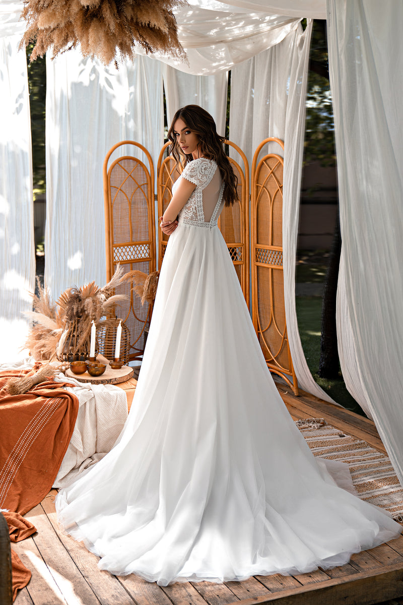 Ivory wedding dress with a lace-trimmed open back, short sleeves, and a long flowing train