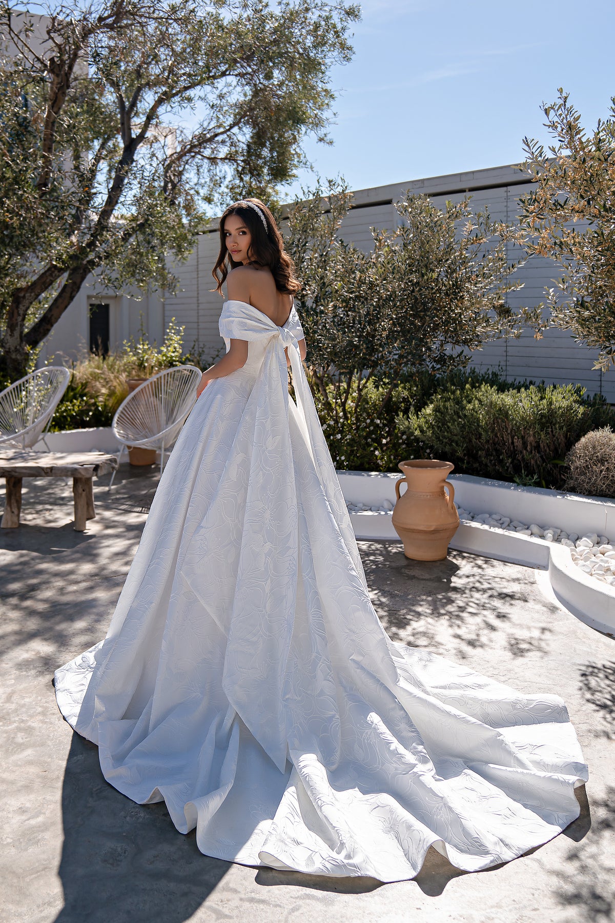 Ivory wedding dress with a full floral-textured skirt, off-the-shoulder sleeves, and sweeping train
