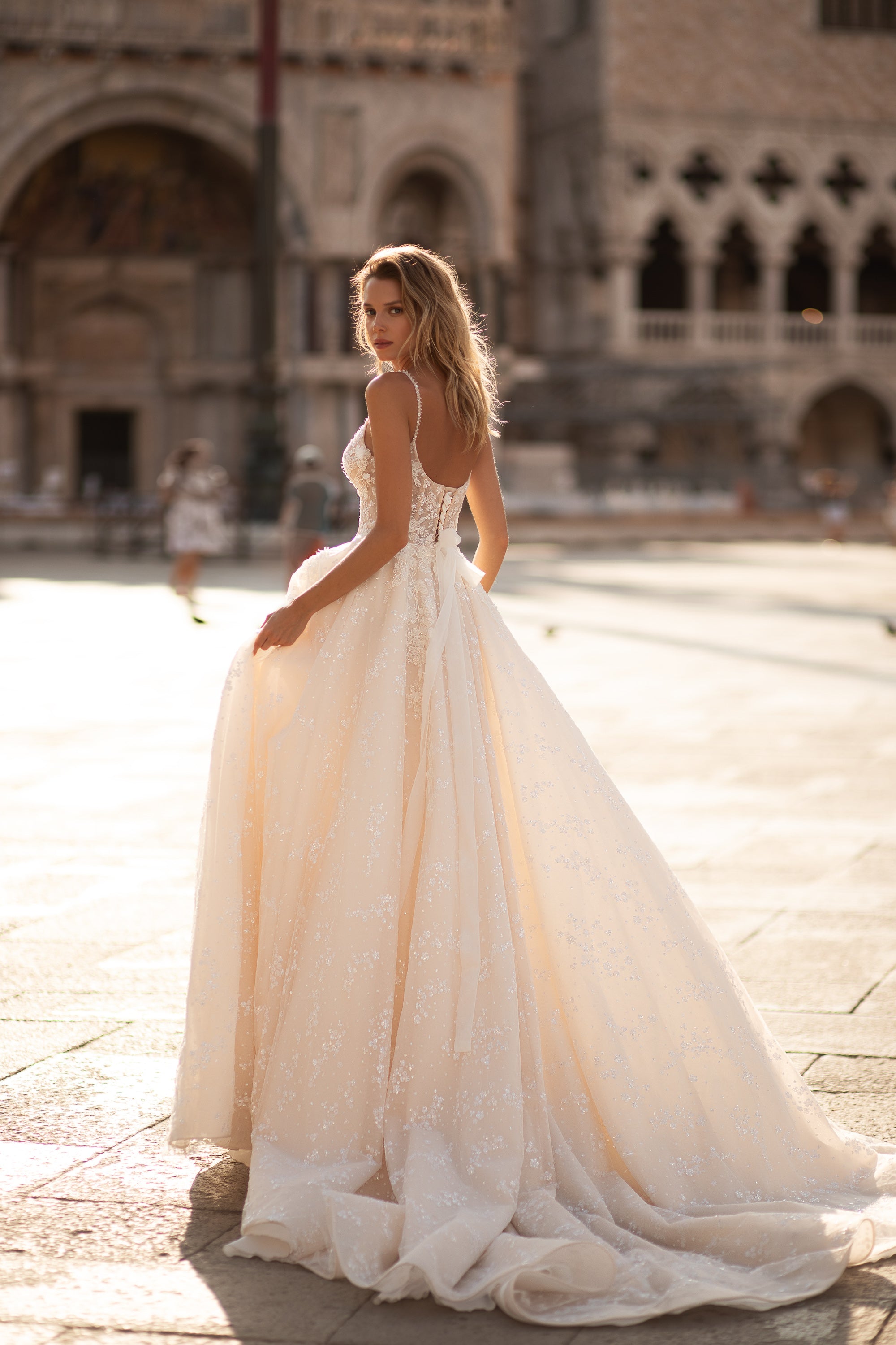 Low open back and floral lace detailing on an ivory A-line wedding dress with a long train