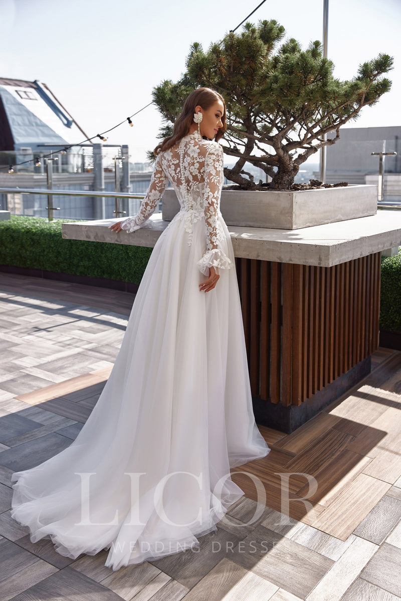 Side-back view of an ivory wedding dress with floral lace sleeves, a fitted waist, and sweeping train