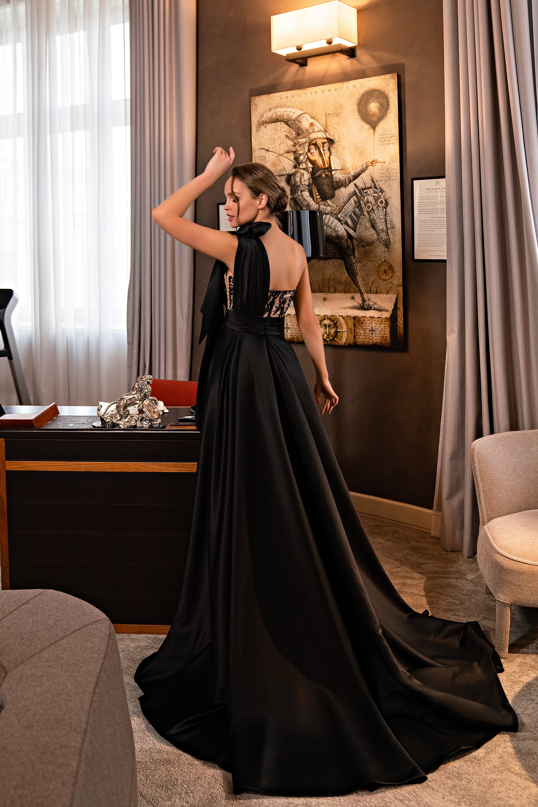 Open-back black evening dress with a lace bodice and dramatically flared satin train