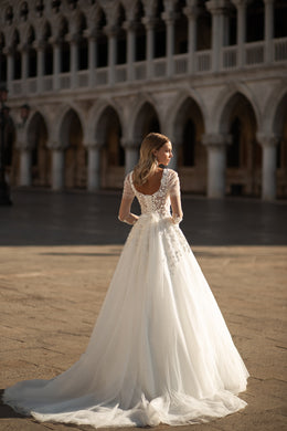 Low scoop back on an ivory wedding dress with lace sleeves, a full A-line skirt, and long train