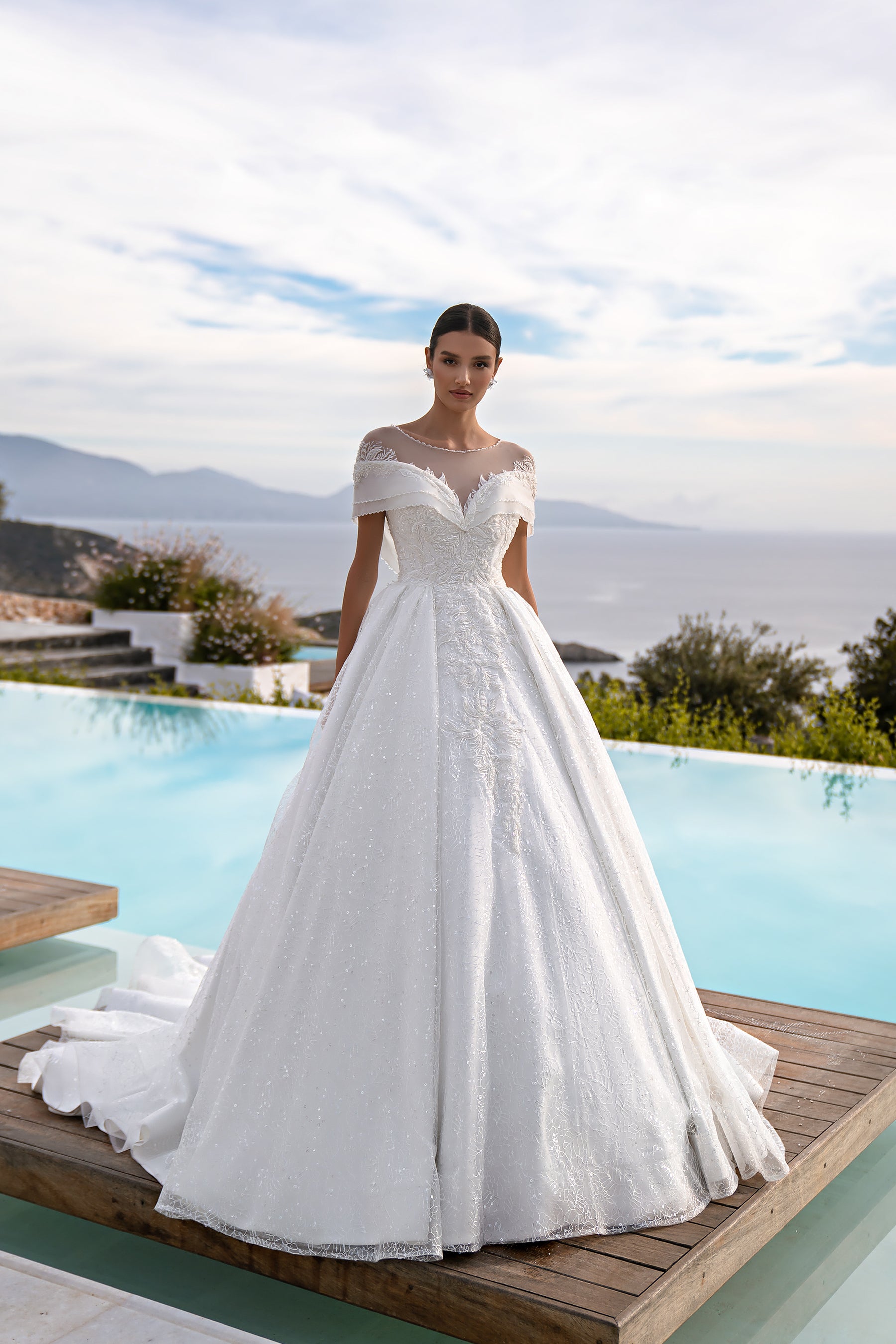 White ball gown wedding dress with illusion neckline, off-shoulder sleeves, sparkling lace, and a wide skirt