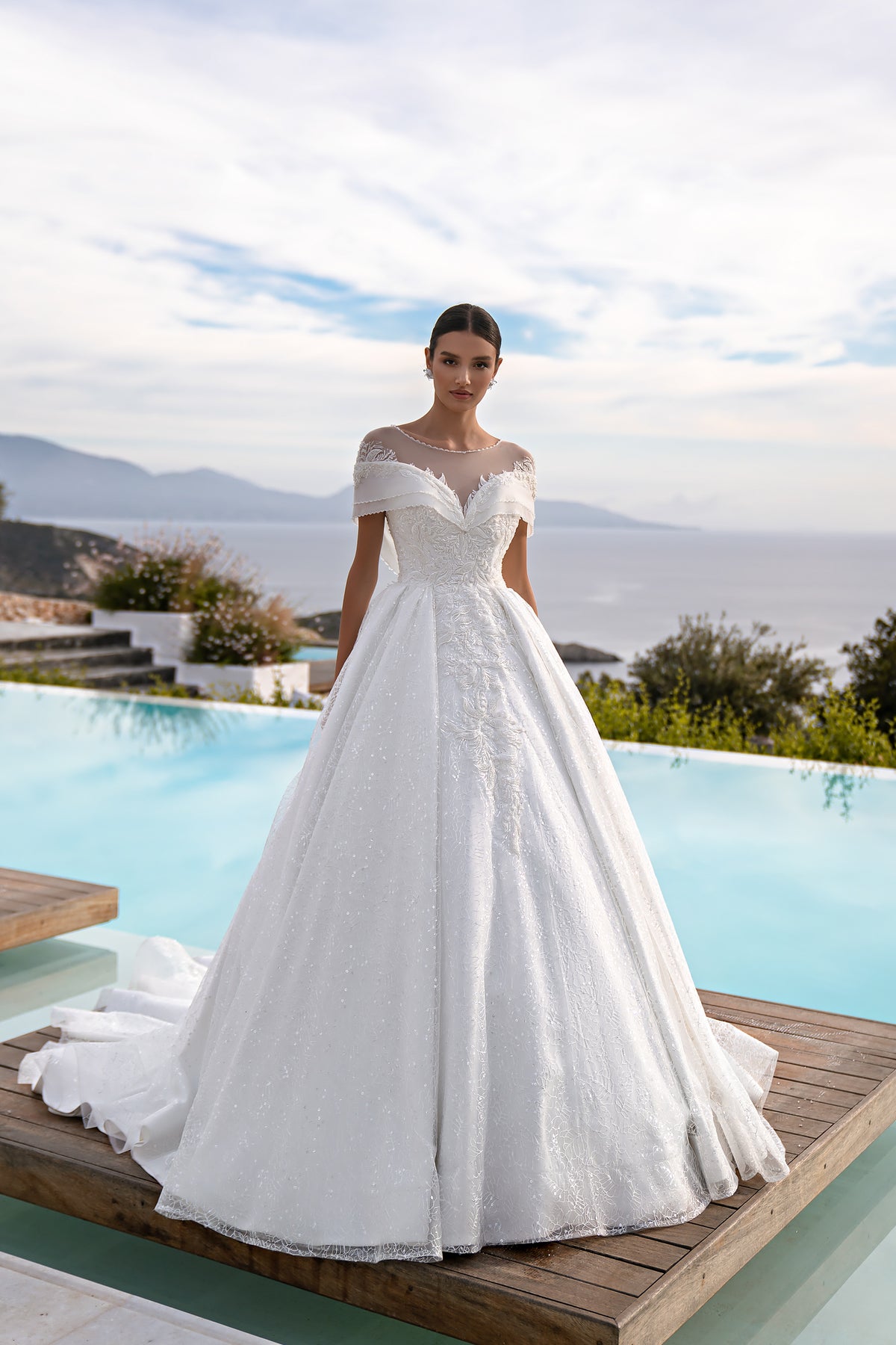 White ball gown wedding dress with illusion neckline, off-shoulder sleeves, sparkling lace, and a wide skirt