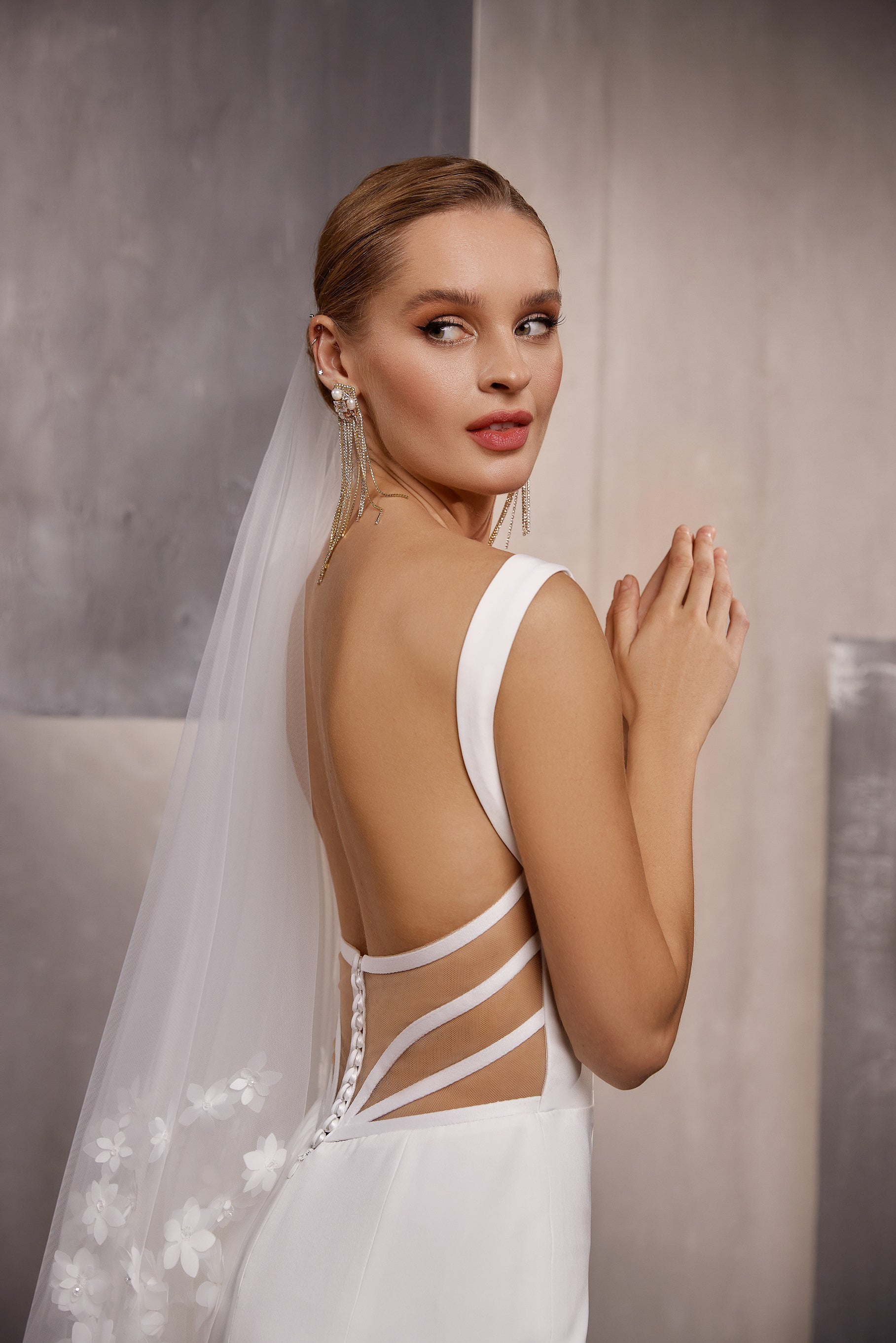 Close-up of a sheer wedding veil with delicate floral embroidery trailing from the bride’s head