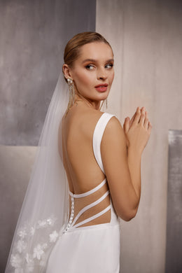 Close-up of a sheer wedding veil with delicate floral embroidery trailing from the bride’s head