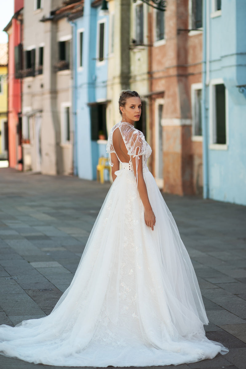Sheer lace back and sweeping train on an ivory wedding dress with short sleeves