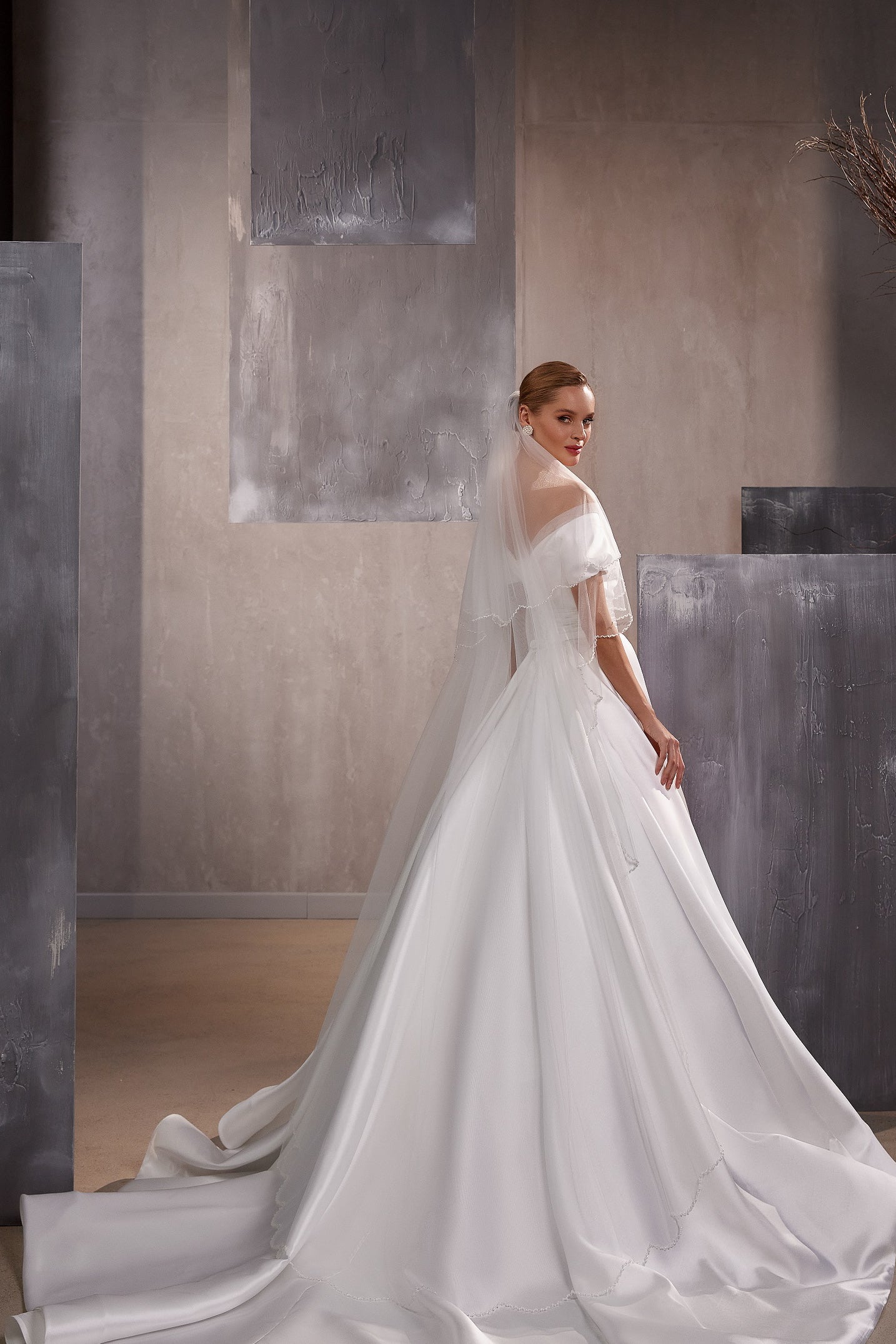 Sheer layered white wedding veil with delicate bead accents and a long trailing edge