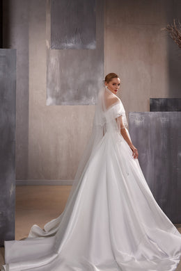 Sheer layered white wedding veil with delicate bead accents and a long trailing edge