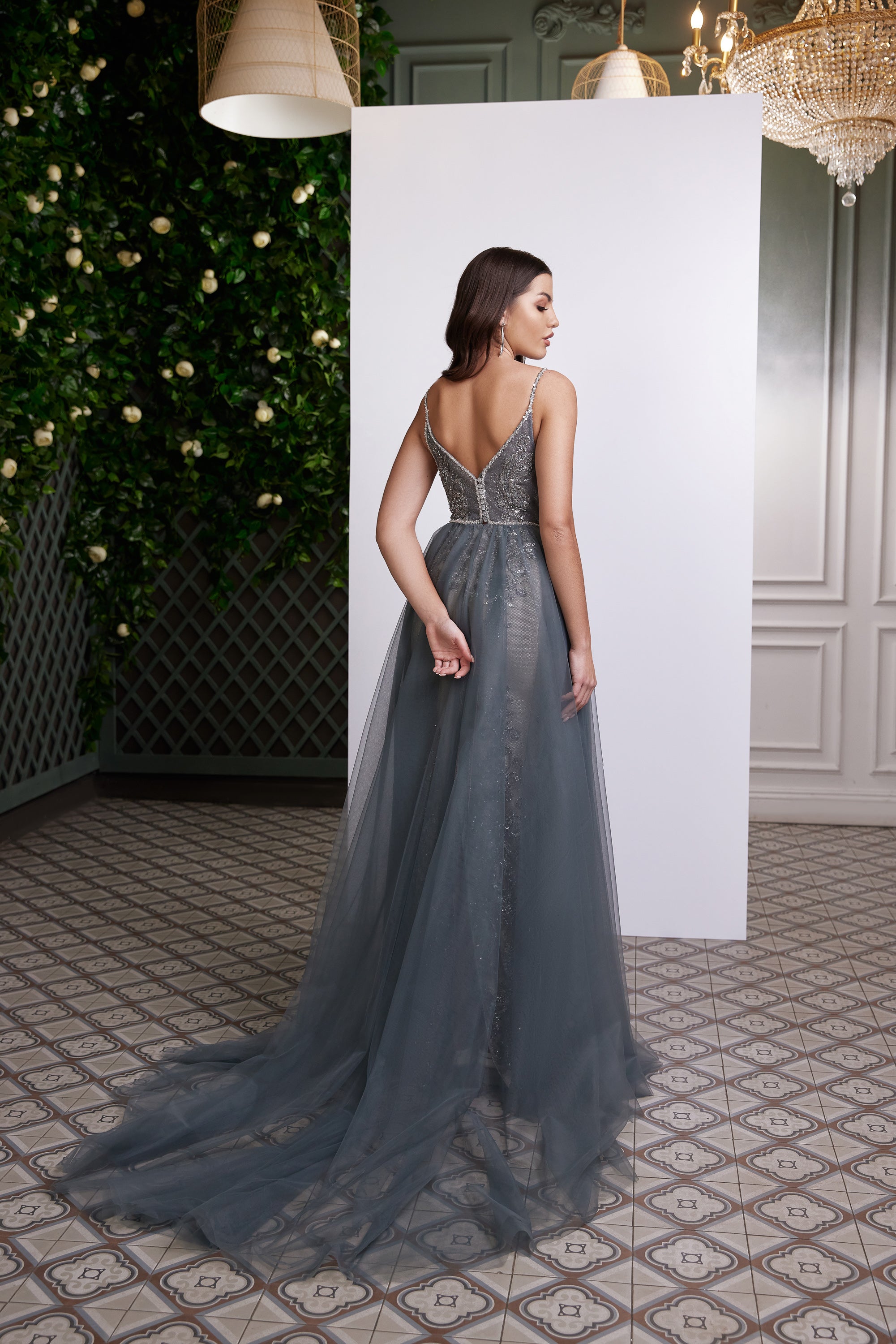 Silver-gray evening dress with an open strappy embellished back, fitted waist, and sweeping sheer train