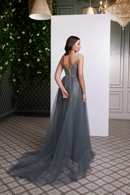 Silver-gray evening dress with an open strappy embellished back, fitted waist, and sweeping sheer train